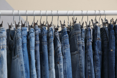 Photo of Rack with stylish jeans on color background, closeup