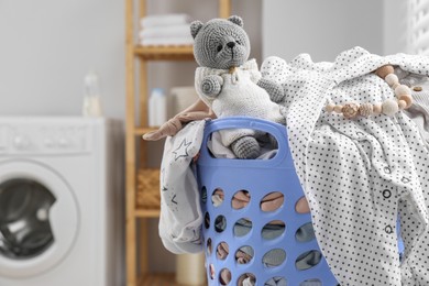 Photo of Laundry basket with baby clothes and crochet toy in bathroom. Space for text