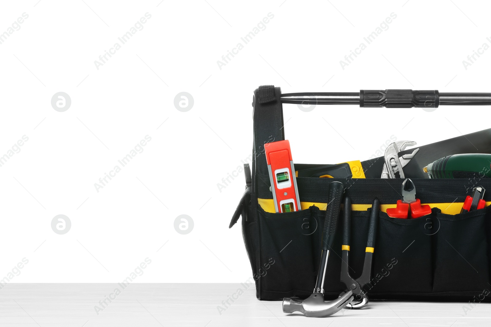 Photo of Bag with different tools on wooden table against white background