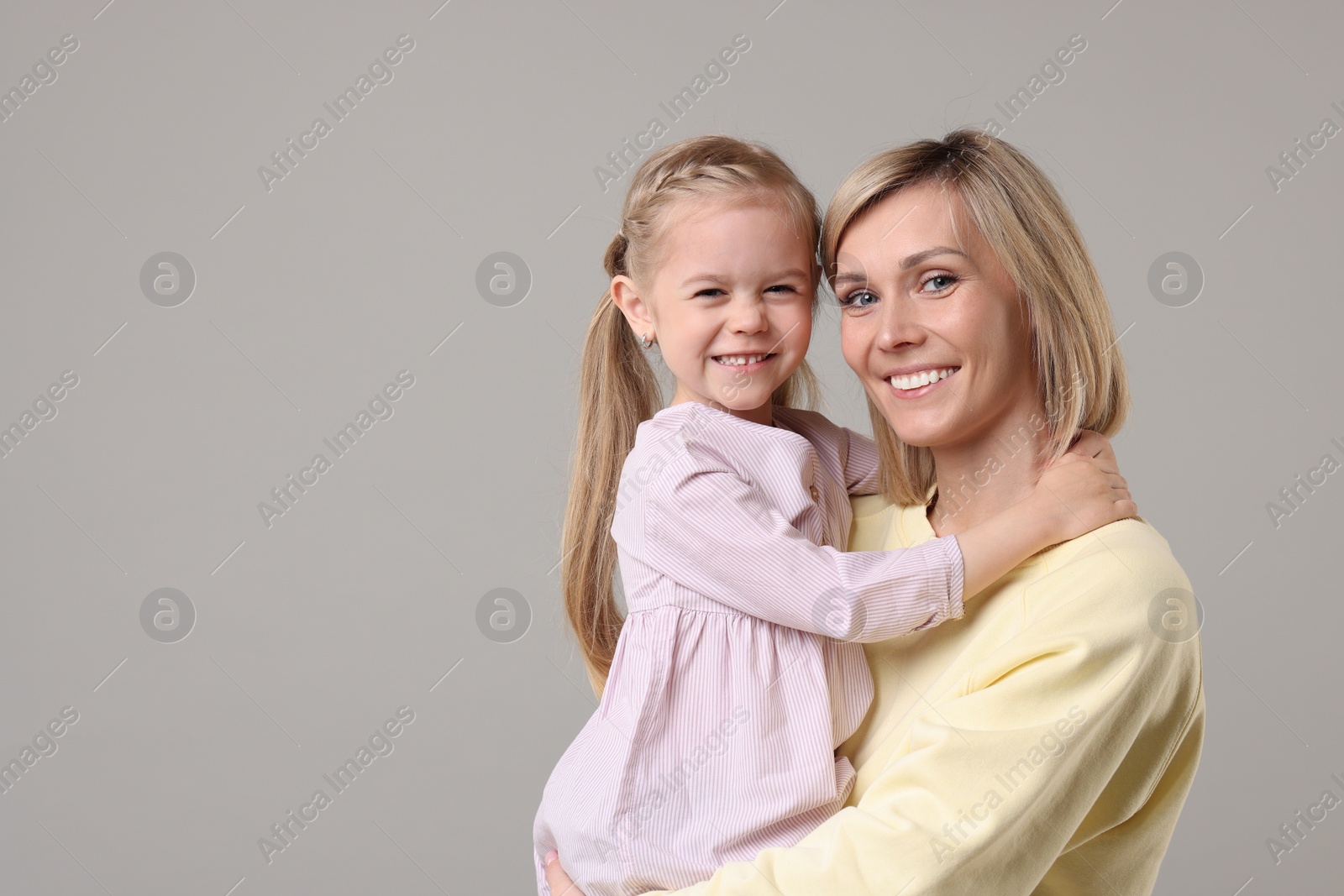 Photo of Family portrait of happy mother and daughter on grey background. Space for text