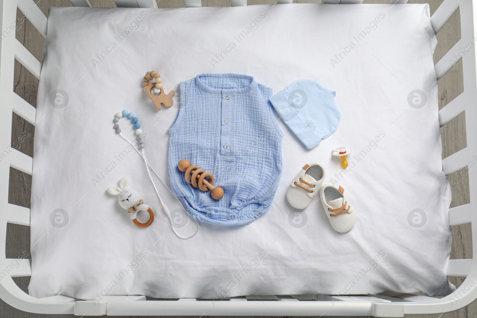 Photo of Flat lay composition with cute baby clothes and accessories on white bedsheet in crib