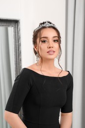 Beautiful young woman wearing luxurious tiara indoors