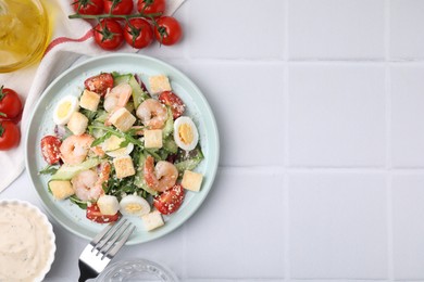 Photo of Delicious Caesar salad with shrimps and ingredients on white tiled table, flat lay. Space for text