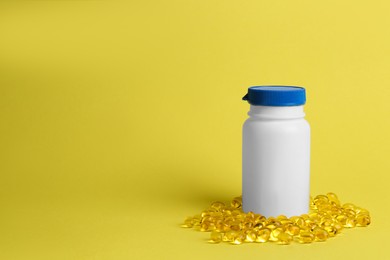 Medicine bottle and pills on yellow background, space for text