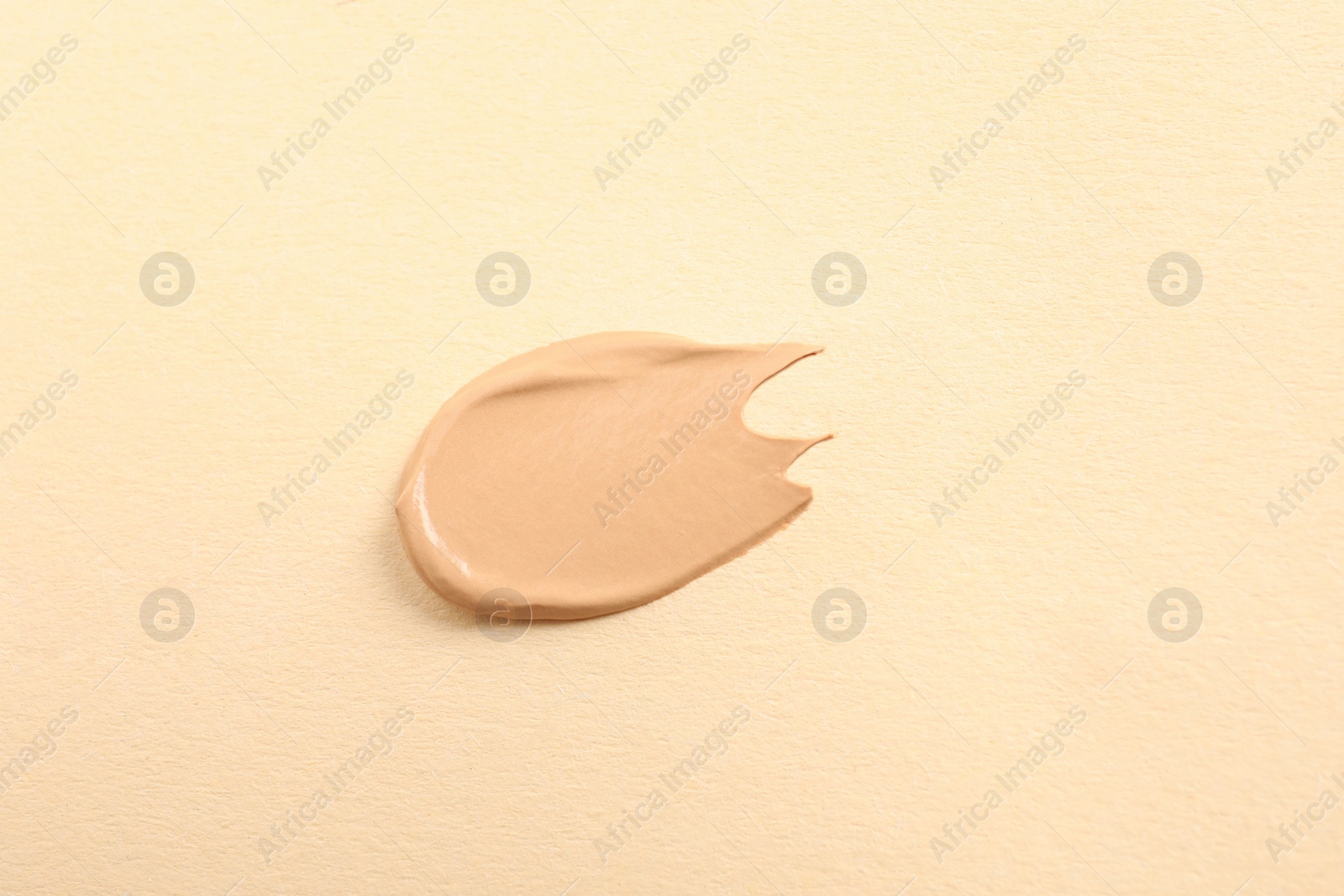 Photo of Smear of skin foundation on beige background, top view