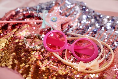 Photo of Stylish carnival costume with sequins, sunglasses, wand and headbands, closeup