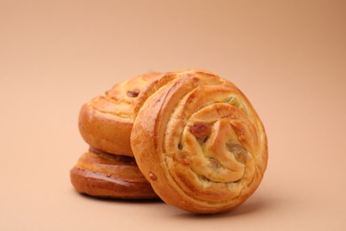 Photo of Delicious rolls with raisins on beige background, closeup. Sweet buns