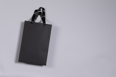 Photo of One black paper shopping bag on grey background, top view. Space for text