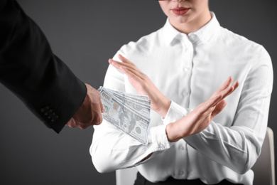 Photo of Woman refuses to take bribe money on dark background, closeup