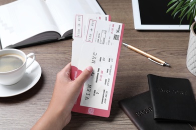 Photo of Woman holding tickets at table, closeup. Travel agency concept