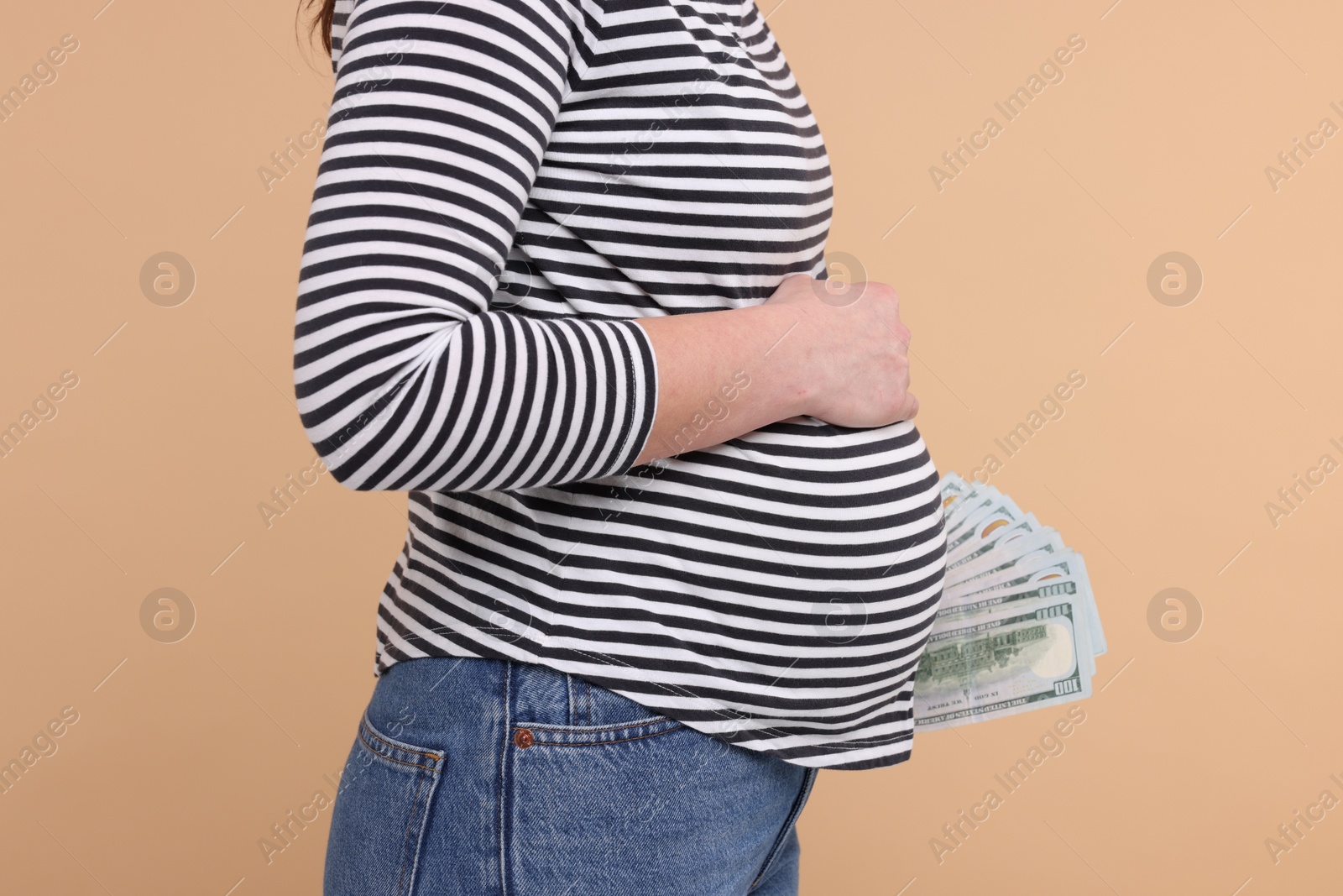 Photo of Surrogate mother. Pregnant woman with dollar banknotes on beige background, closeup