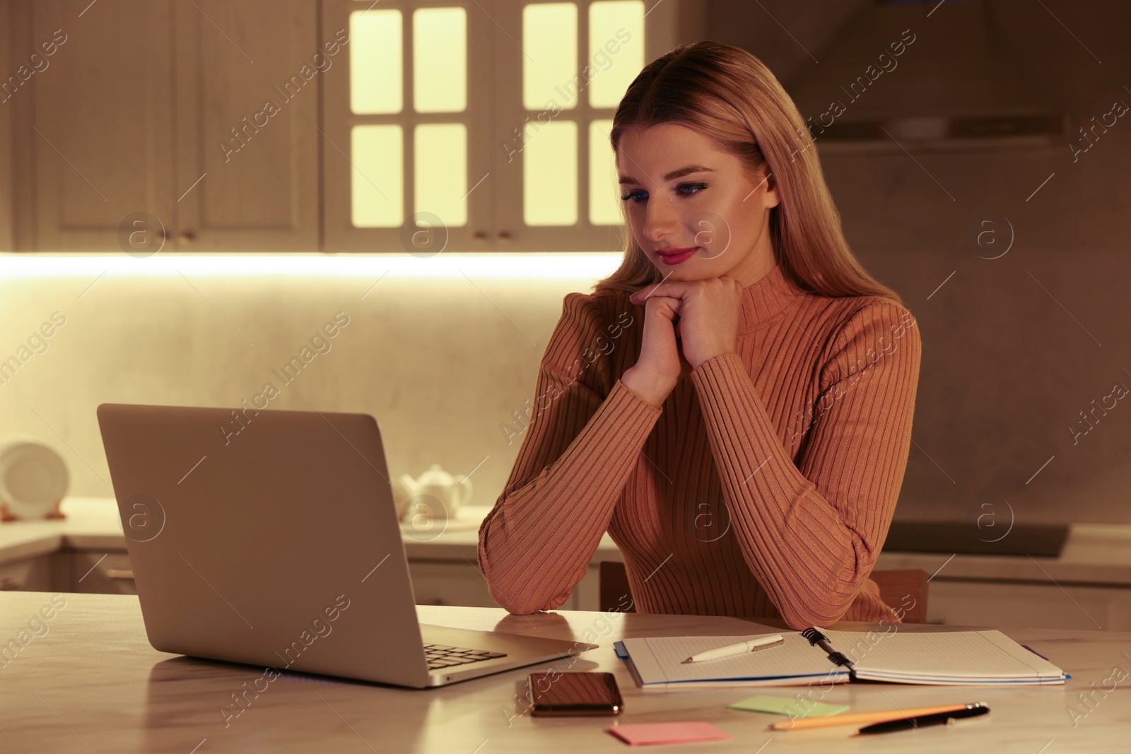 Photo of Home workplace. Woman looking at laptop at marble desk in kitchen