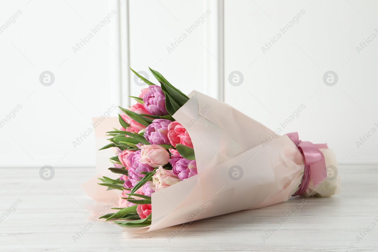 Photo of Bouquet of beautiful tulips on white wooden table