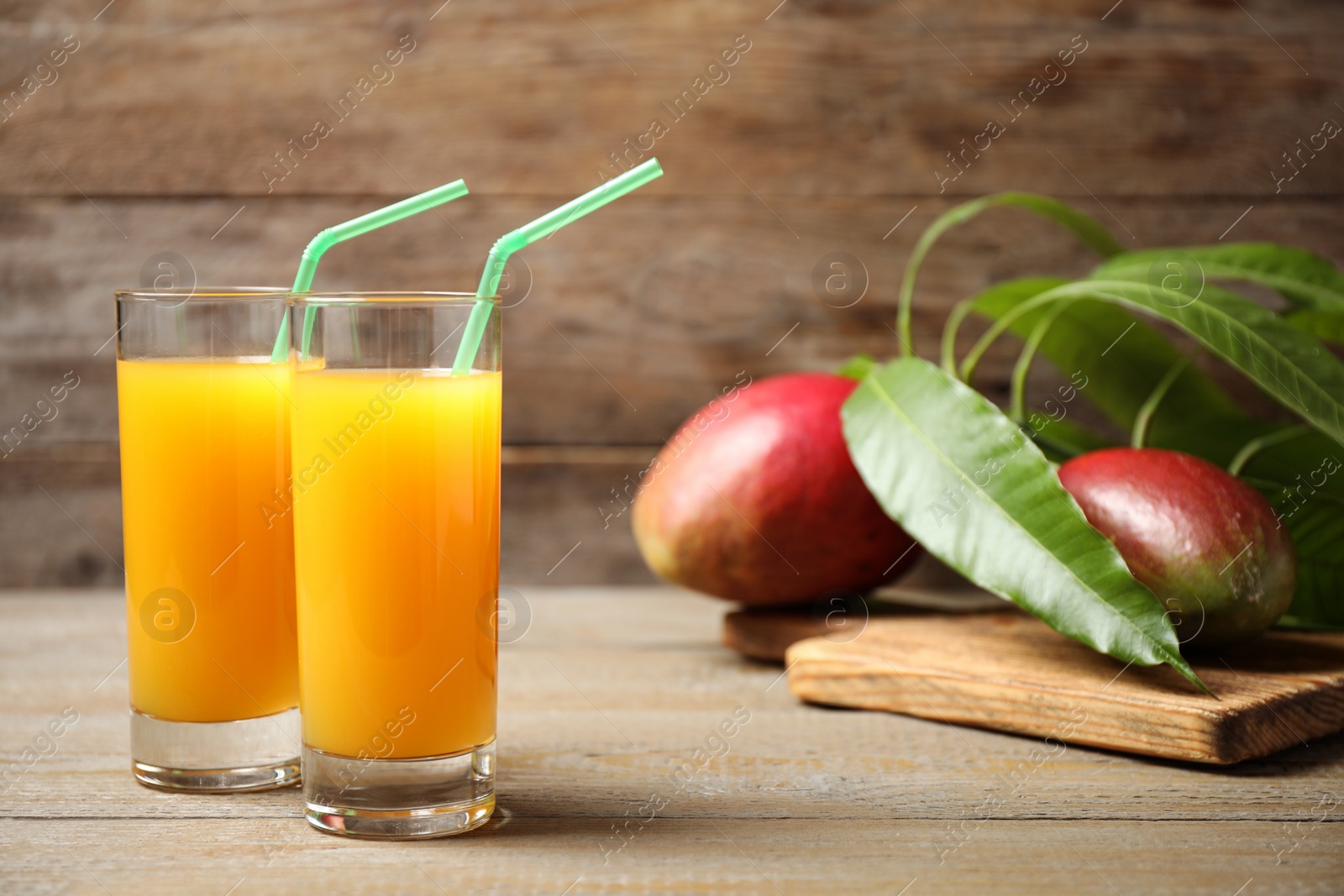 Photo of Fresh delicious mango drink on wooden table. Space for text