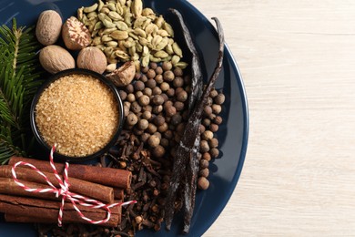 Photo of Different aromatic spices and fir branches on light wooden table, top view. Space for text