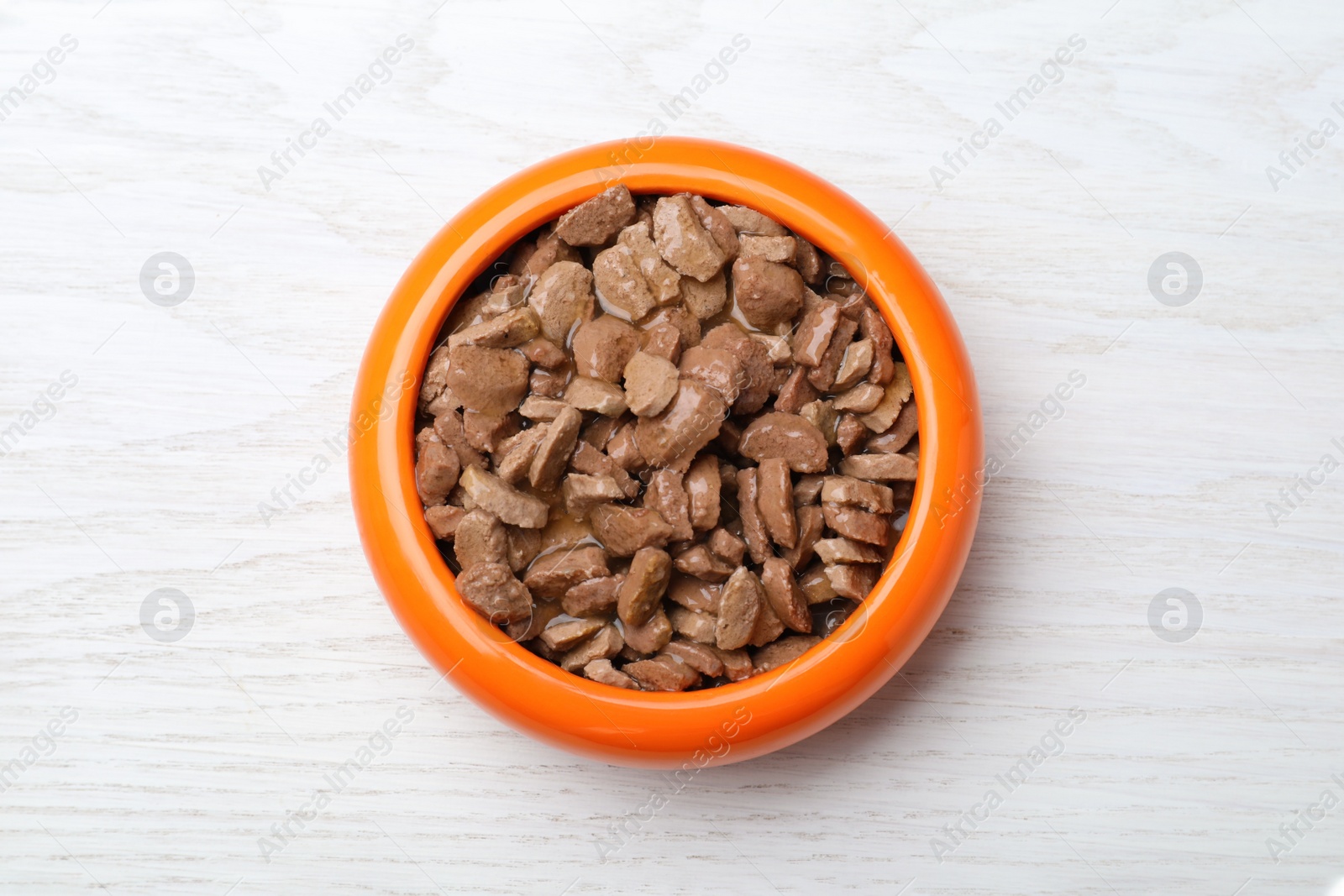 Photo of Wet pet food in feeding bowl on white wooden table, top view