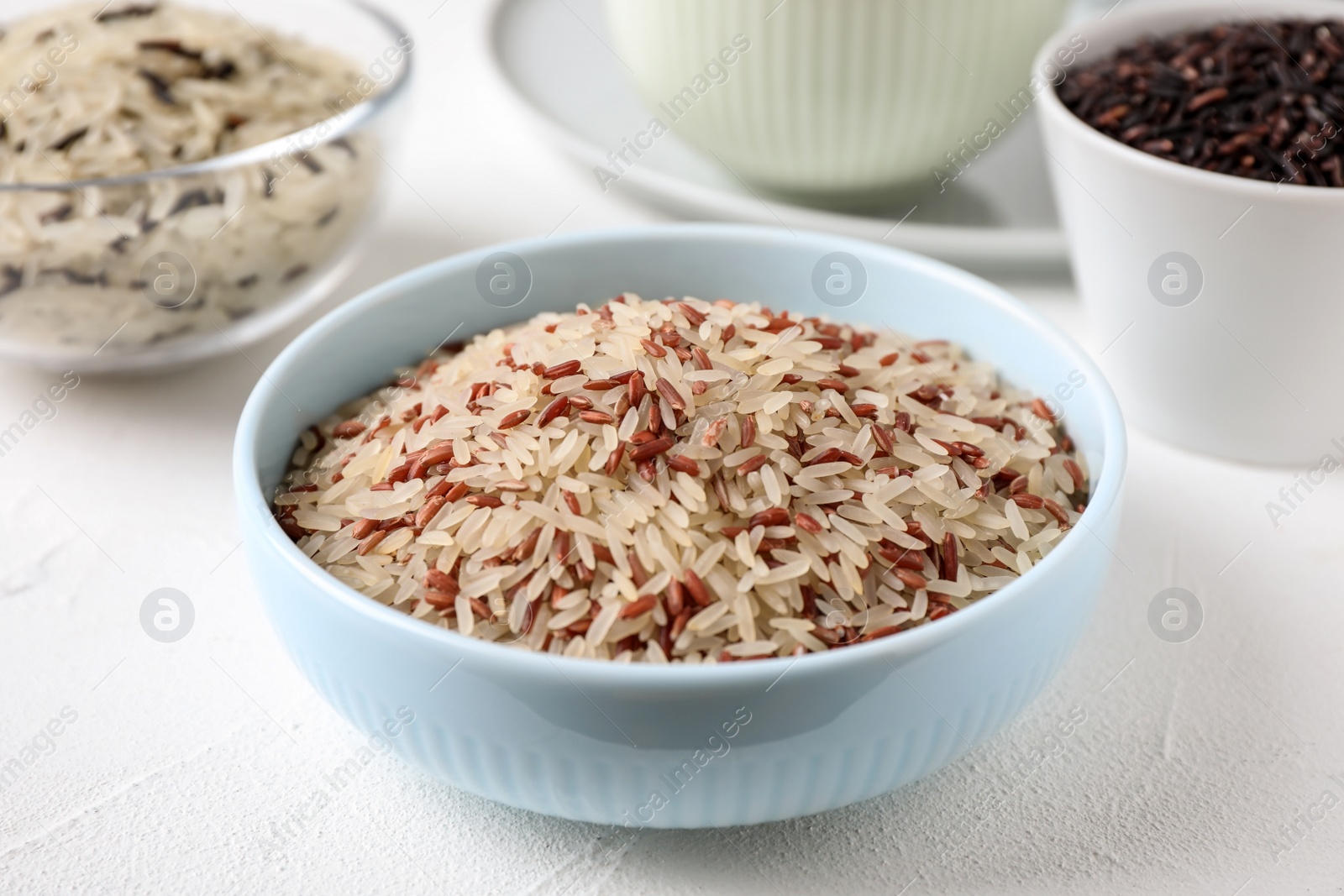 Photo of Mix of brown and polished rice on white table, closeup