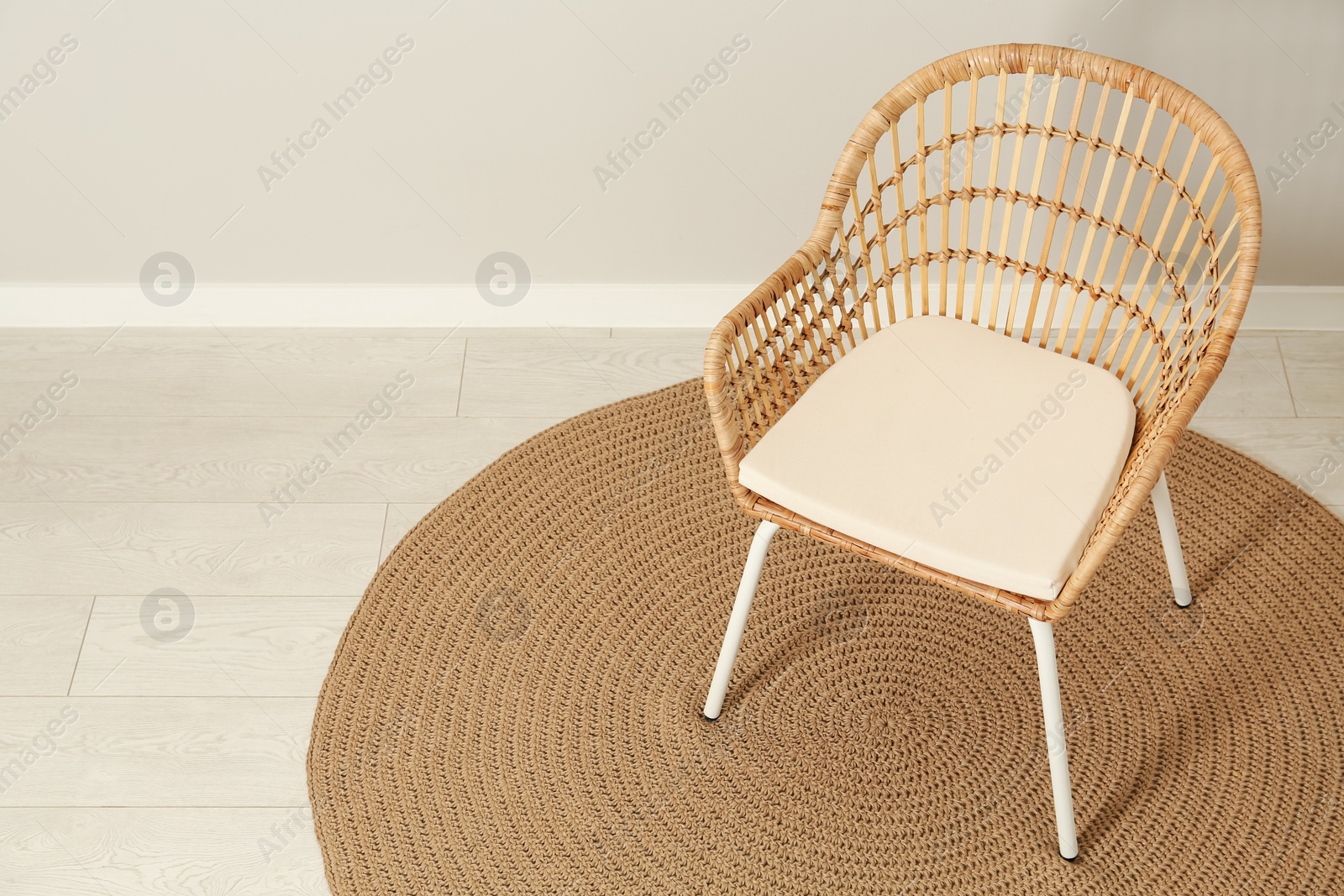 Photo of Wicker armchair near light wall in room. Space for text