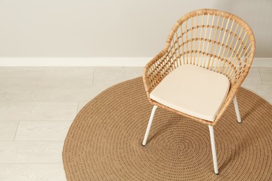 Photo of Wicker armchair near light wall in room. Space for text