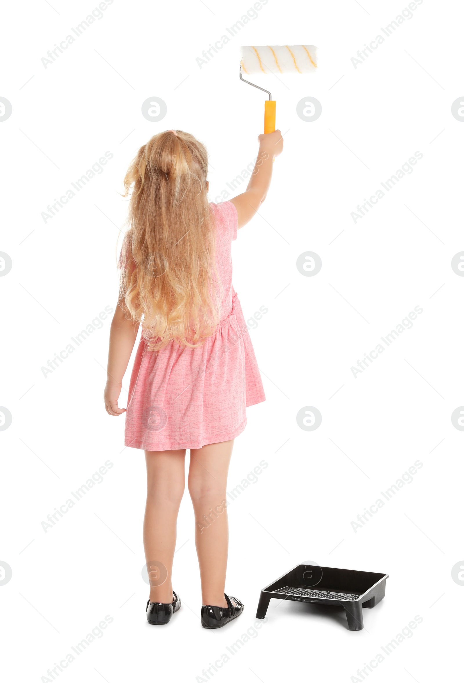 Photo of Little child painting something with roller brush on white background