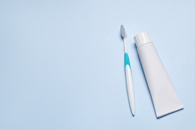 Plastic toothbrush and paste on light background, flat lay. Space for text
