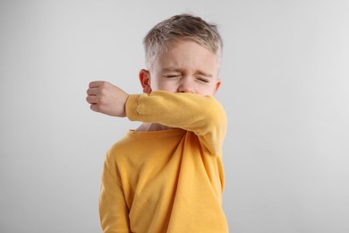 Photo of Sick boy coughing on gray background. Cold symptoms