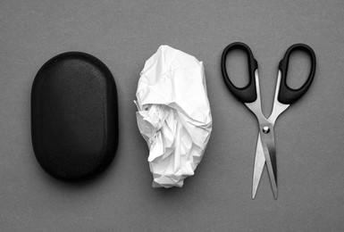 Photo of Rock, crumpled paper and scissors on gray background, flat lay