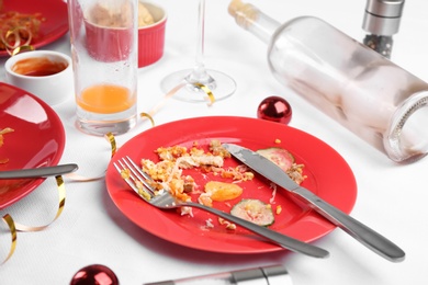 Photo of Dirty plate with leftovers on white tablecloth after party