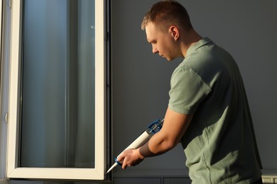 Photo of Construction worker sealing window with caulk indoors