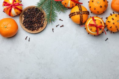 Photo of Pomander balls made of tangerines with cloves and fir branch on grey table, flat lay. Space for text