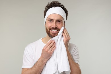 Photo of Washing face. Man with headband and towel on light grey background