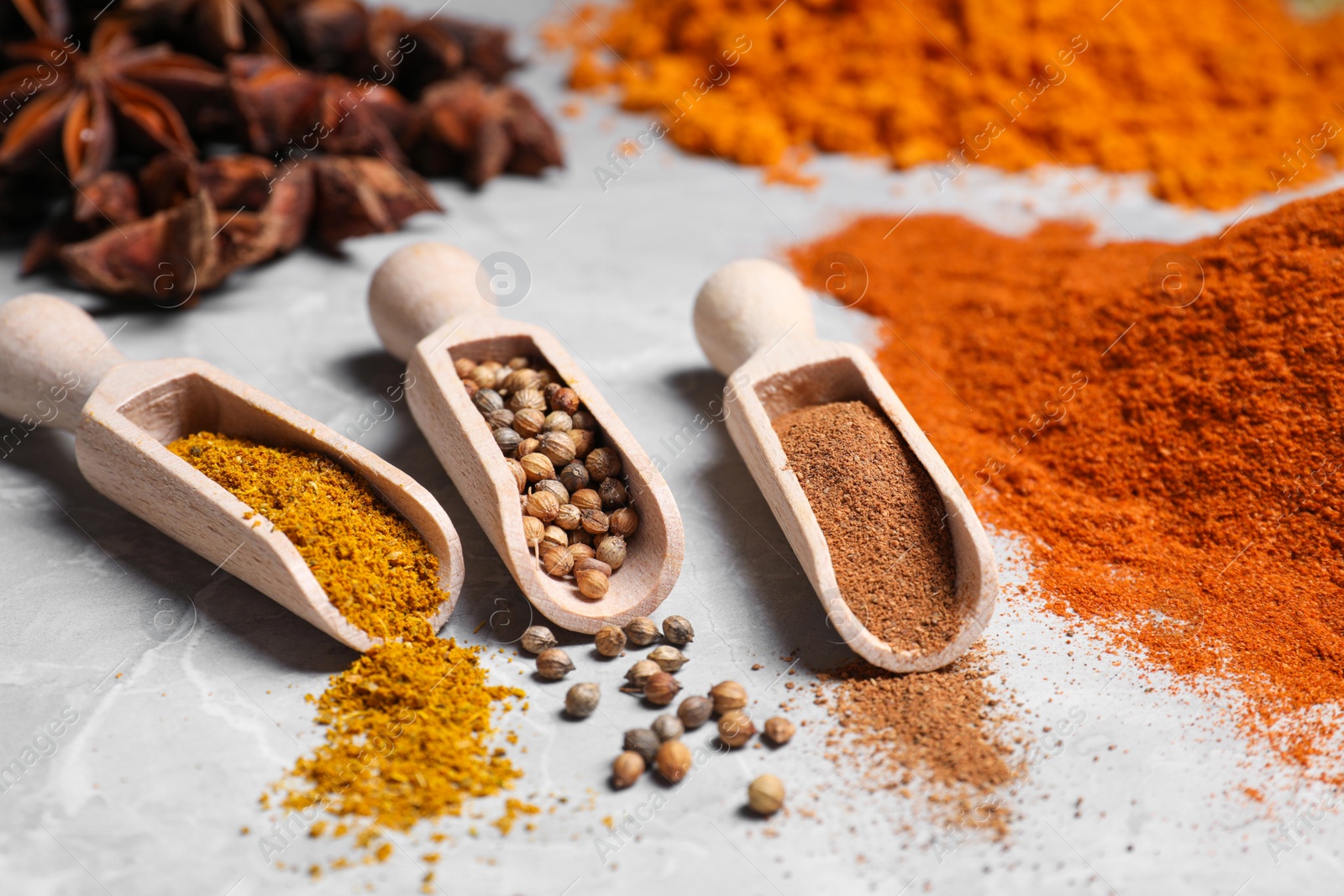 Photo of Scoops with different spices on gray marble table, closeup