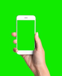 Image of Young woman holding smartphone with green screen on color background, closeup. Mockup for design