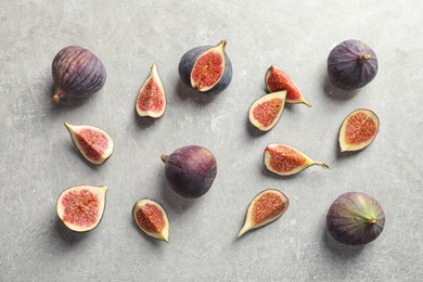 Flat lay composition with whole and cut purple figs on gray background