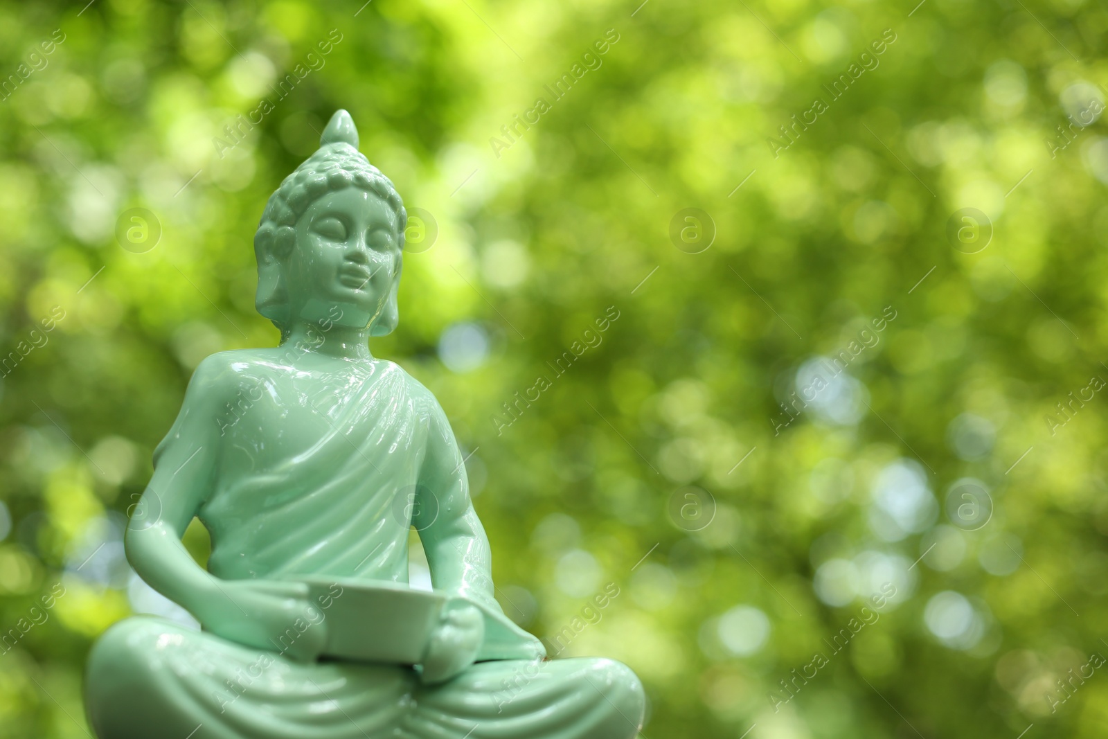 Photo of Decorative Buddha statue on blurred background, closeup. Space for text