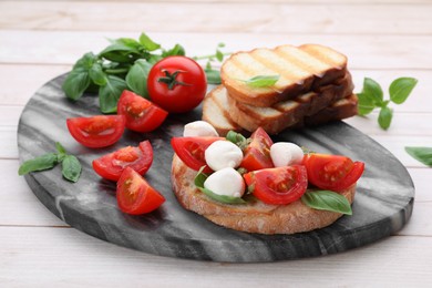 Photo of Delicious Caprese sandwich with mozzarella, tomatoes, basil and pesto sauce on white wooden table