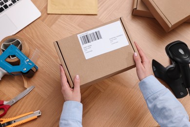 Photo of Post office worker packing parcel at wooden table, top view