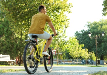 Photo of Handsome young man with bicycle in city park