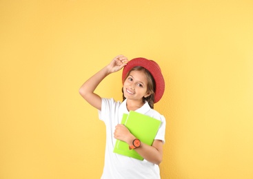 Pretty preteen girl with notebooks against color background