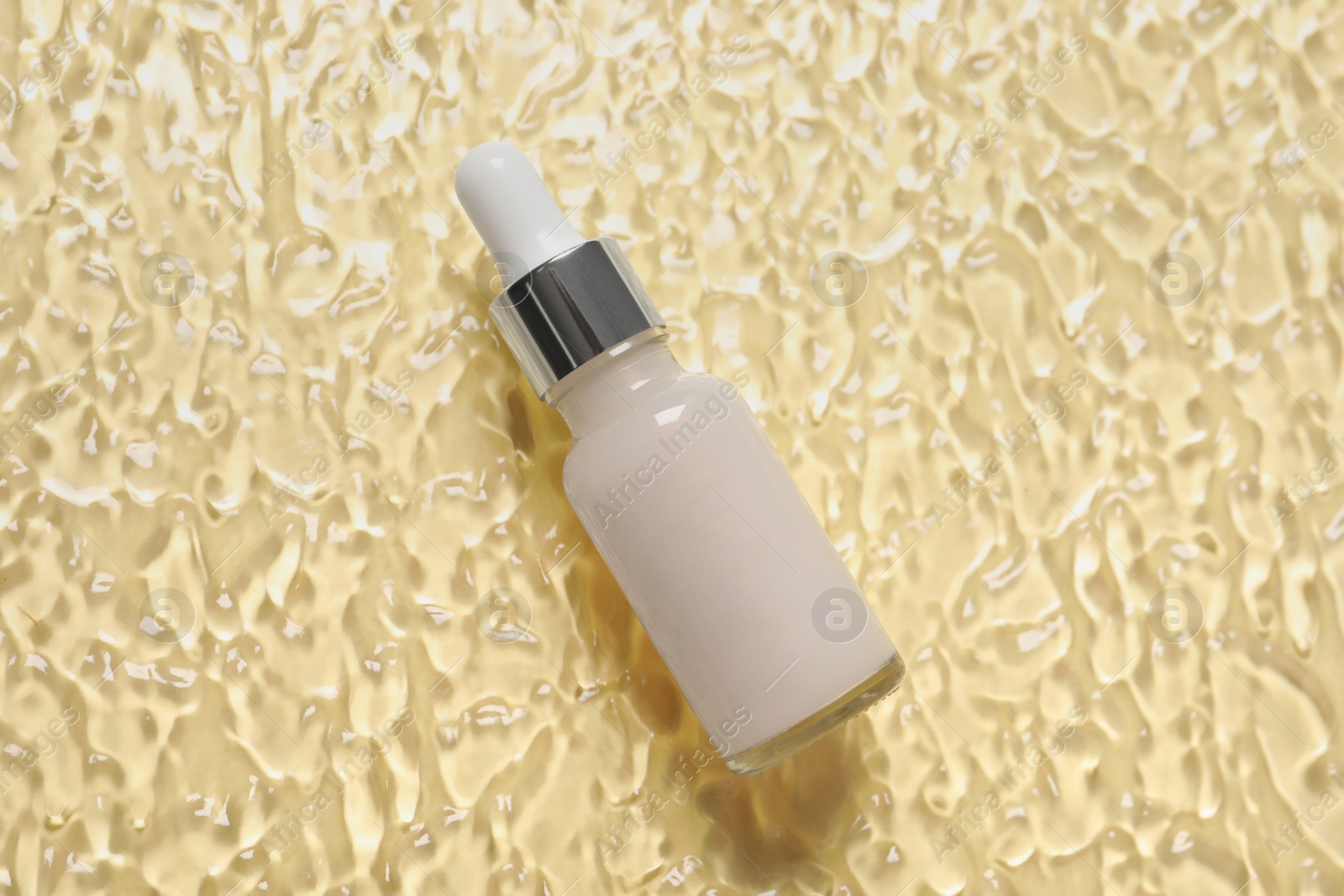 Photo of Bottle of cosmetic serum on beige background, top view