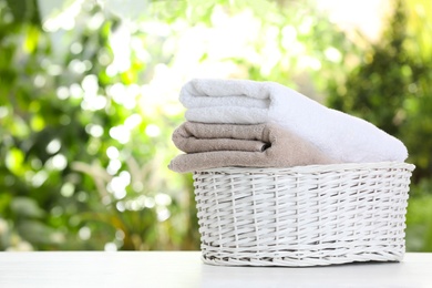 Photo of Basket with soft bath towels on table against blurred background. Space for text