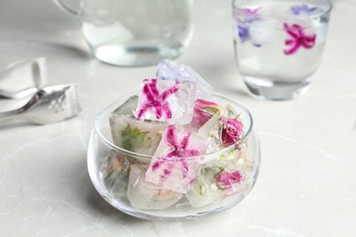 Glass bowl of floral ice cubes on table