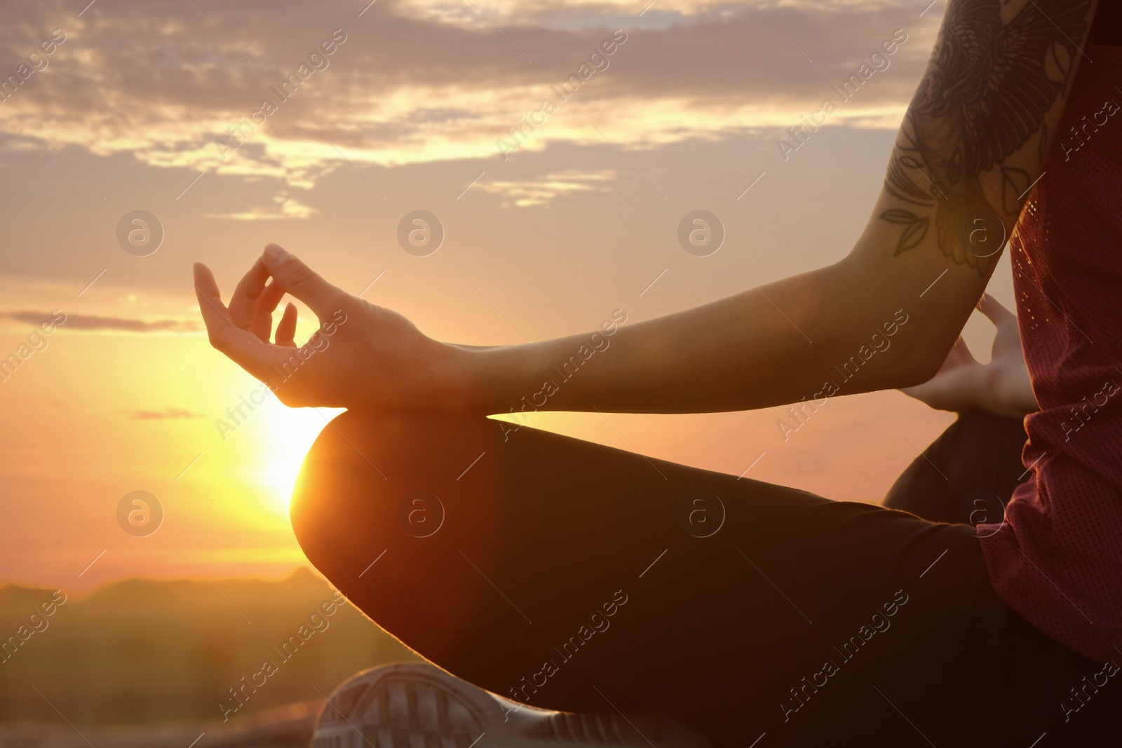 Photo of Young woman practicing zen yoga at sunrise outdoors, closeup