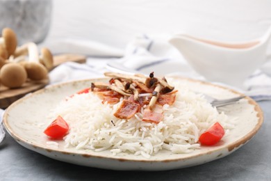 Photo of Delicious rice with bacon, mushrooms and tomatoes served on table, closeup