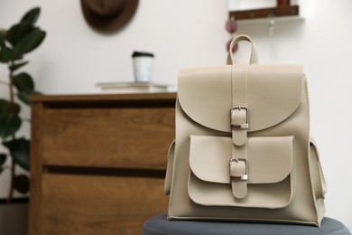 Photo of Stylish urban backpack on stool in hallway. Space for text