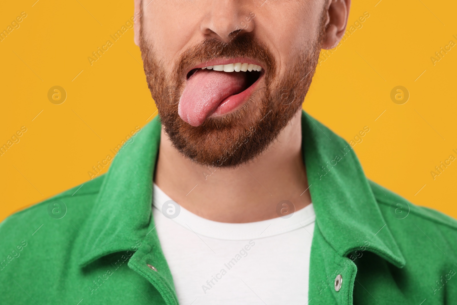 Photo of Man showing his tongue on orange background, closeup