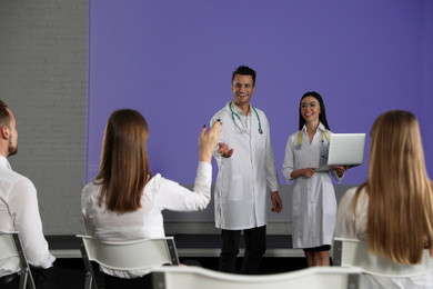 Young doctors with laptop giving lecture in conference room with projection screen