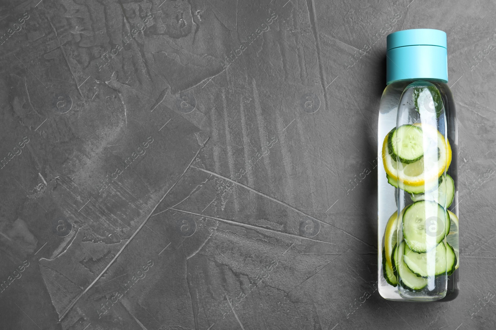 Photo of Bottle of refreshing water with cucumber, lemon and mint on black table, top view. Space for text