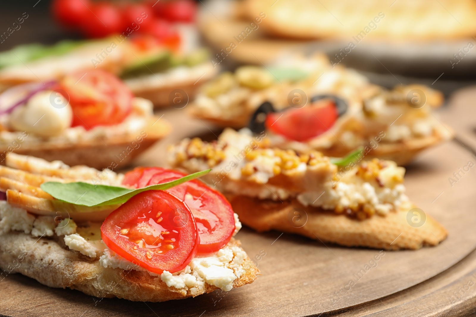 Photo of Delicious chicken bruschettas on wooden board, closeup