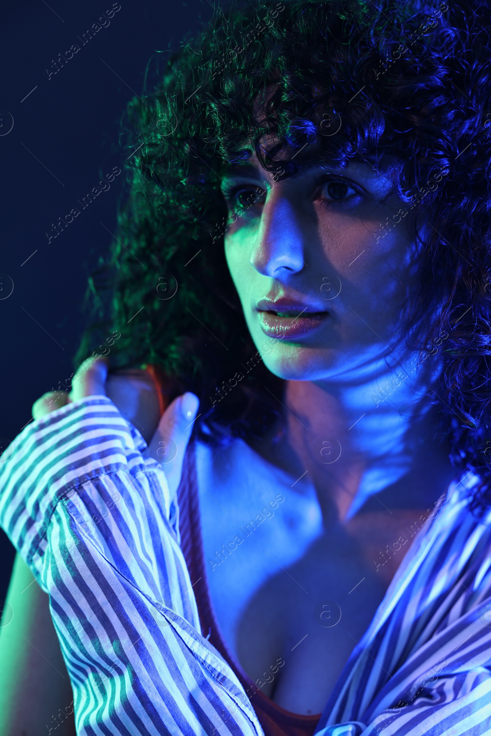 Photo of Beautiful young woman posing on color background in neon lights, closeup